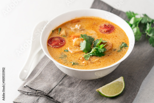 Tom yum soup with shrimps in white bowl on light background with copy space. Popular traditional asian cuisine