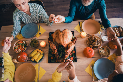 Above view cropped portrait of big friendly family hold arms pray celebrate thanksgiving day dinner flat indoors photo