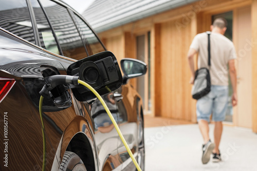 Принти на полотні Young man plugging a charger in electric car at modern house home