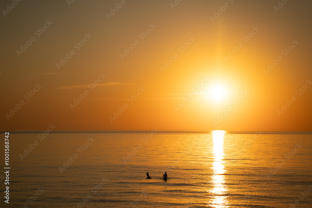pinkish orange seawater against a orange western sky pinkish orange seawater against a orange western sky