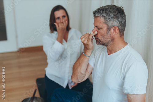 Photography A man sitting in lotus position and a woman practicing alternate nostril breathi
