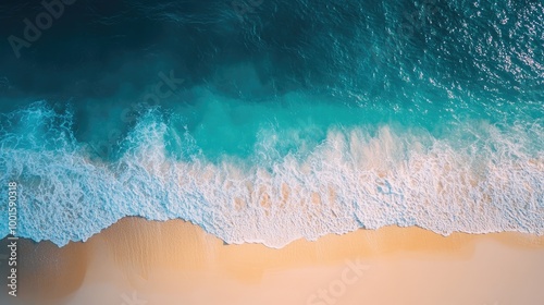Fototapeta Naklejka Na Ścianę i Meble -  Top-down shot of a crystal-clear blue sea with sunlight sparkling on the waves and a golden sandy beach