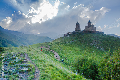 The Gergeti Trinity Church stands tall against a dramatic sky, overlooking a lush green valley.