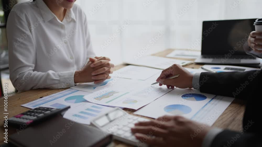 Businessman pointing at charts during a corporate meeting, discussing data and strategies with a colleague at the office