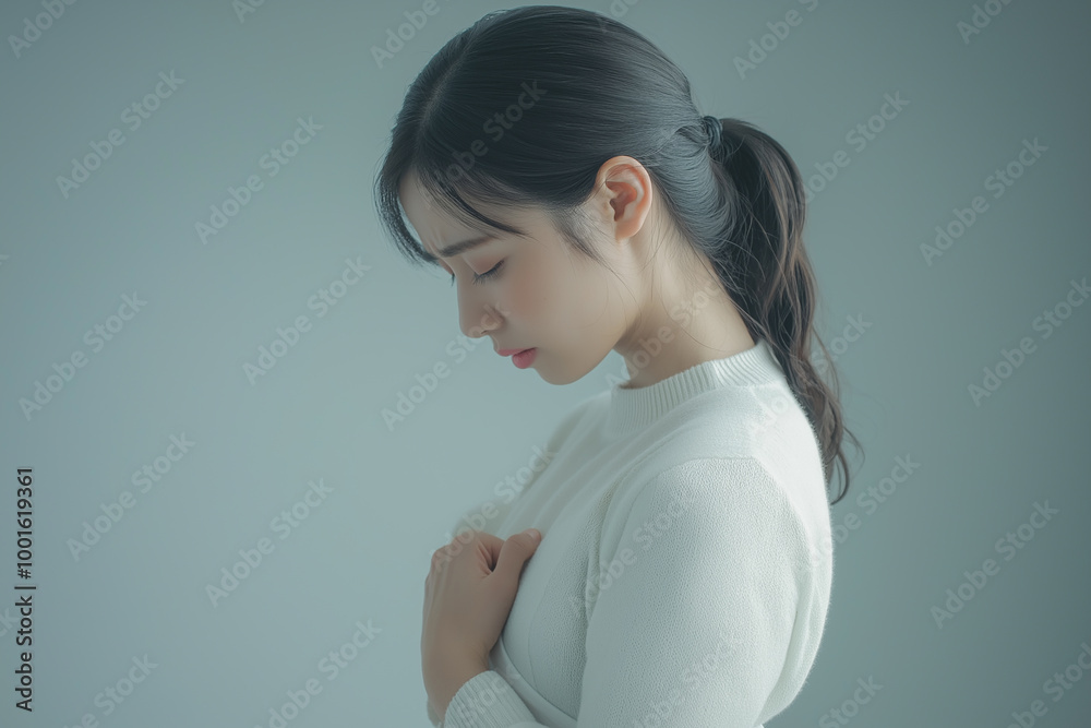 Young woman holding chest in pain or discomfort, symbolizing emotional and physical struggles related to health and wellness challenges Young woman holding chest in pain or discomfort, symbolizing emotional and physical struggles related to health and wellness challenges