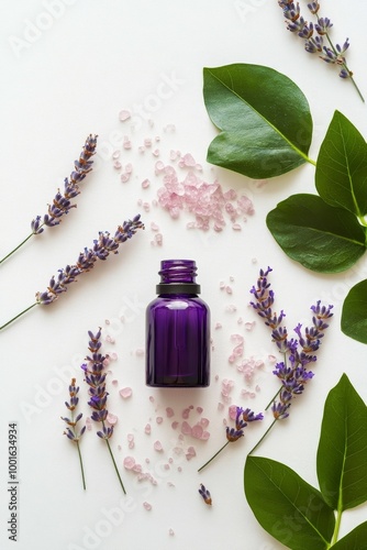 Lavender essential oil bottle surrounded by flowers and leaves on a white sur...