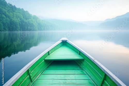 Early morning mist over a tranquil lake viewed from a green wooden boat