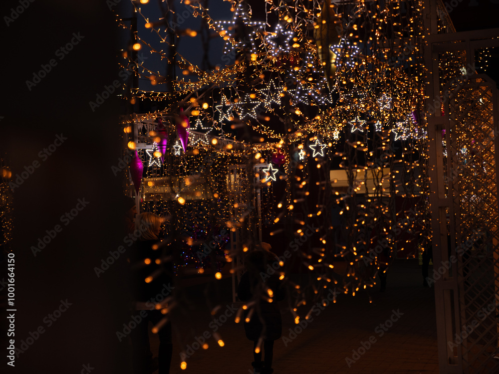 Christmas and New Year holidays decorations of streets with trees and shops with multicolored christmas string fairy lights glowing in the darkness outdoors. Winter holidays celebration concept.