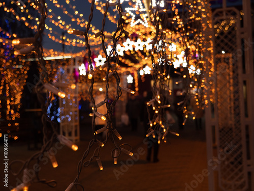 Obraz na płótnie Christmas and New Year holidays decorations of streets with trees and shops with multicolored christmas string fairy lights glowing in the darkness outdoors. Winter holidays celebration concept. w salonie