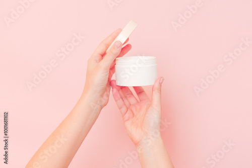 Round jar of cosmetic cream in hand on pink background. Cosmetics beauty mockup for product branding