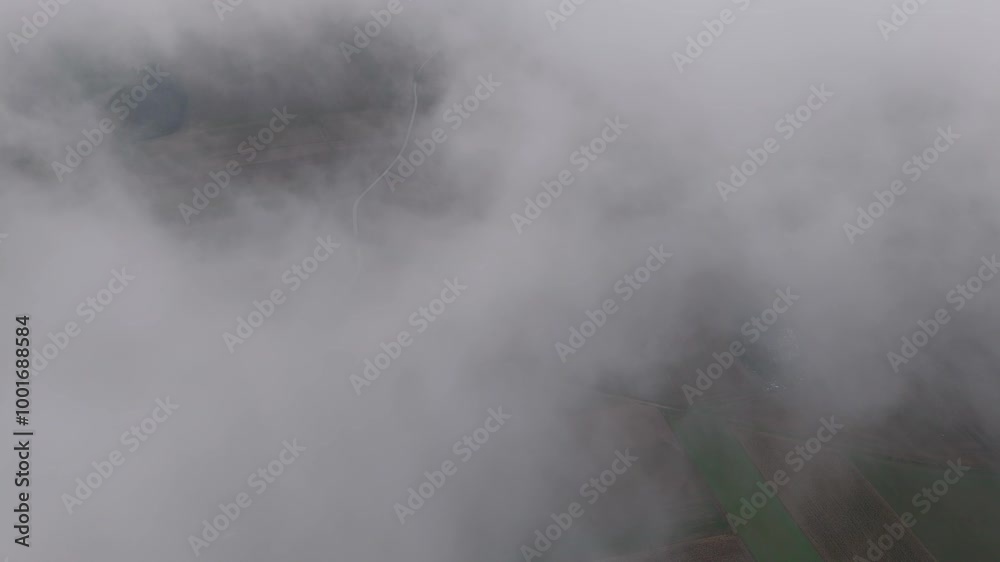 Aerial view of a winding road between fields on a rainy, overcast day. The road stretches to the horizon, with a distant city and a river that has overflowed its banks. Aerial view of a winding road between fields on a rainy, overcast day. The road stretches to the horizon, with a distant city and a river that has overflowed its banks.