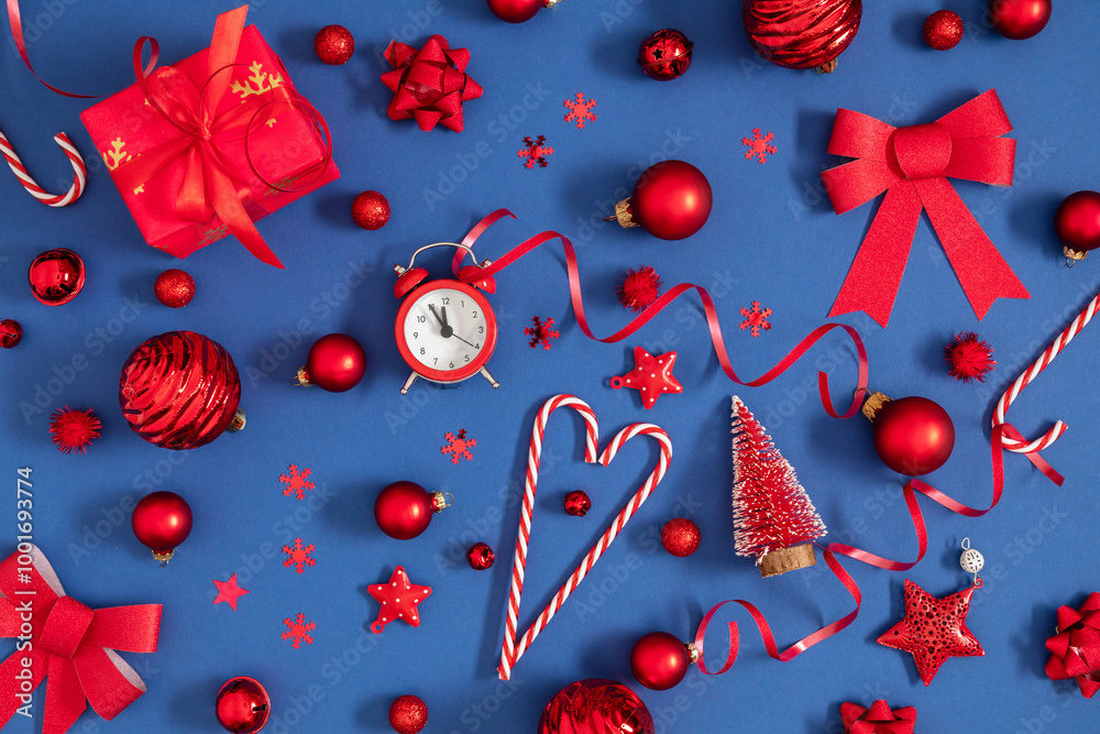 Fototapeta premium Christmas background, pattern. Beautiful, modern festive Christmas composition with red different Xmas decorations. Balls, alarm clock, heart, confetti on dark blue background. Flat lay