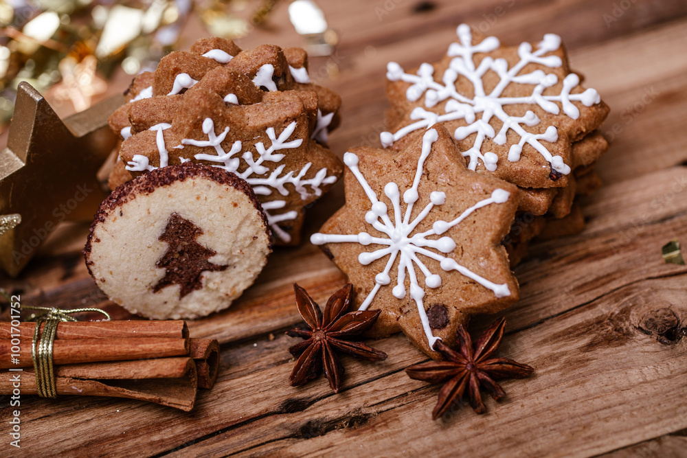 Gingerbread star cookies with white icing and a round cookie with a tree design on a wooden table, accompanied by cinnamon sticks, star anise, a gold star ornament, and festive bokeh lights. Gingerbread star cookies with white icing and a round cookie with a tree design on a wooden table, accompanied by cinnamon sticks, star anise, a gold star ornament, and festive bokeh lights.