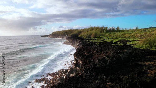 Aerial drone footage of Waiʻānapanapa State Park ocean shore on Maui island in Hawaii, USA. Travelling view showing waves breaking on the black rock coast photo