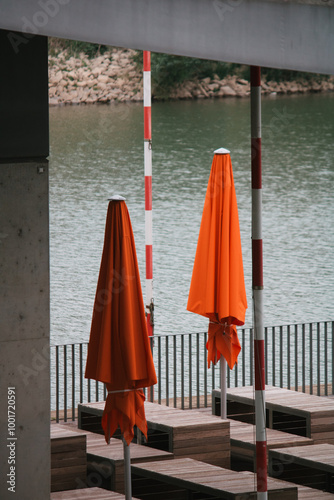 Geschlossene orangefarbene Sonnenschirme an einem Flussufer photo