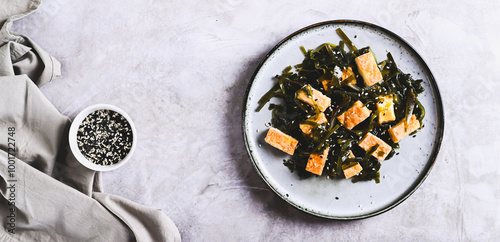 Seaweed salad with fried soy tofu cheese on plate on table top view web banner