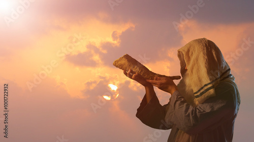 the silhouett of  Jewish man blowing the Shofar horn of Rosh Hashanah New Year on sunset