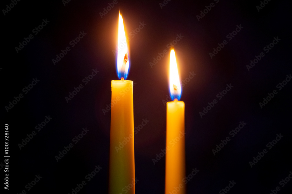 two candles with bright flames at night on a black background, Christmas celebration two candles with bright flames at night on a black background, Christmas celebration