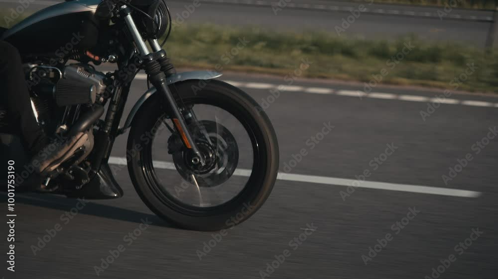 Man in black helmet and black leather jacket rides motorcycle at high speed along highway surrounded by trees. Man in black helmet and black leather jacket rides motorcycle at high speed along highway surrounded by trees.