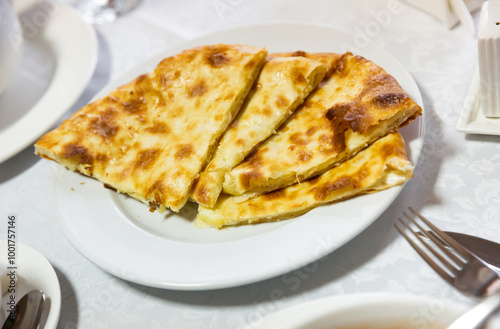 Georgian national delicious flatbread khachapuri with cheese, cut into pieces on a plate..
