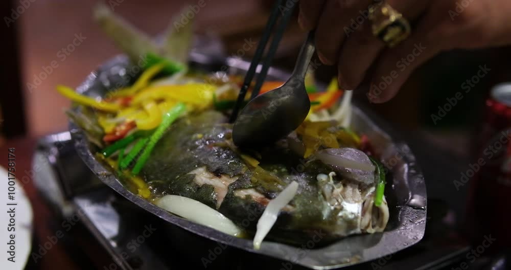Fried white pomfret is a must-have New Year dish In Vietnam, delicious fish is cooked in frying pan in a restaurant, immediately cooked in front of customers. boiling and bubbling in water Fried white pomfret is a must-have New Year dish In Vietnam, delicious fish is cooked in frying pan in a restaurant, immediately cooked in front of customers. boiling and bubbling in water