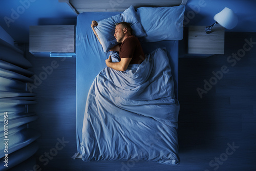 Top view of single middle aged man peacefully sleeping alone in bed at night at home, full length horizontal shot with free space photo