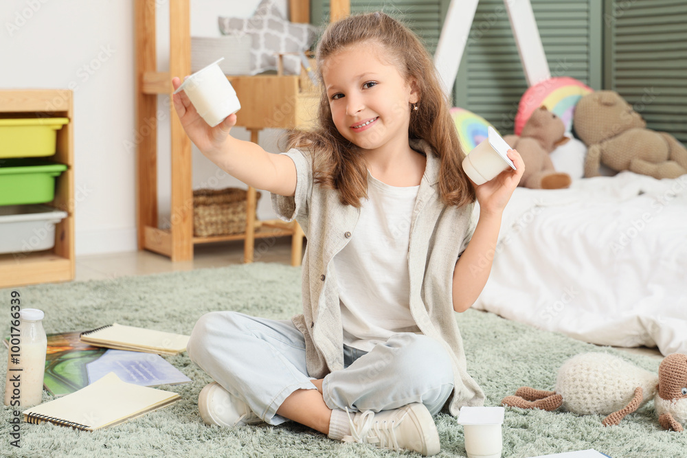 Happy little girl with yogurt packs sitting on floor in room Happy little girl with yogurt packs sitting on floor in room