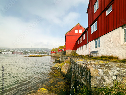 Red Scandinavian style buildings with grass rooftops on the rocky shoreline of the North Atlantic Ocean. Large ships are moored in the harbor of Tórshavn, the Capital city of the Faroe Islands. photo