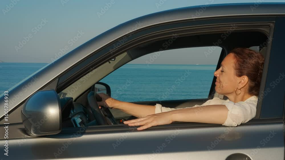 Lady at sea holiday by car in summer. A woman resting by wheel in the car during sea trip in the sun light. Lady at sea holiday by car in summer. A woman resting by wheel in the car during sea trip in the sun light.