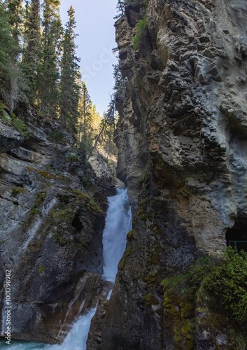 vetical view of a tall waterfall in between tall rocky cliffs in summer with rushing water photo