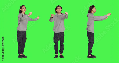Asian man acting as choir director for musical show, moving hands like a choirmaster chief over greenscreen backdrop. Male person conducting band to sing, smiling choirmaster musician.