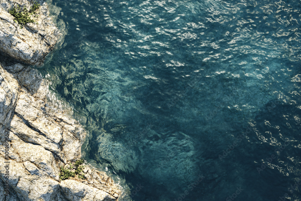 A rocky shoreline with large rocks leads into a clear blue ocean with gentle ripples on the surface creating a peaceful coastal scene A rocky shoreline with large rocks leads into a clear blue ocean with gentle ripples on the surface creating a peaceful coastal scene