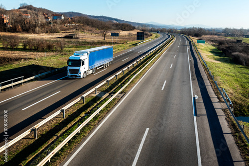 Big white truck with a blue trailer with space for text on a countryside road in motion