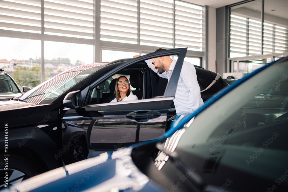 Salesman and woman share smile in car dealership interaction. Salesman and woman share smile in car dealership interaction.