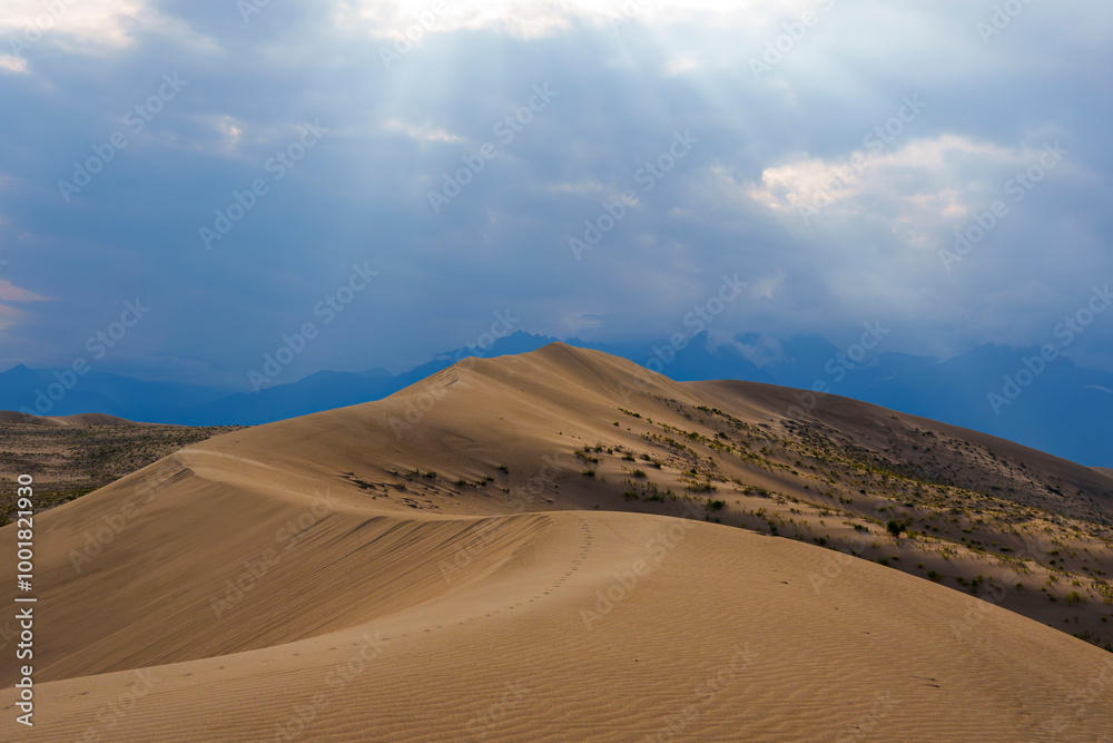 Dramatic desert dunes under sunbeams and cloudy sky Dramatic desert dunes under sunbeams and cloudy sky
