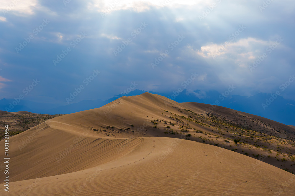 Dramatic desert dunes under sunbeams and cloudy sky Dramatic desert dunes under sunbeams and cloudy sky
