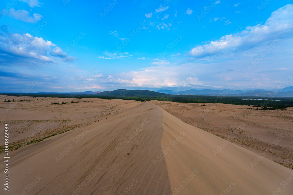 Expansive desert dunes under a dramatic sky with distant mountains Expansive desert dunes under a dramatic sky with distant mountains