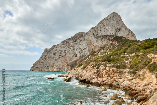 Coastal paradise with azure waters crashing against rocky cliffs under clear blue sky in sunny Calpe Spain tourism