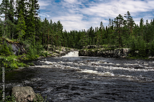 Sognstupet Waterfall cascades into the Storån River, surrounded by lush pine forests, showcasing the natural beauty of Idre in Dalarna, Sweden, on a calm day. photo