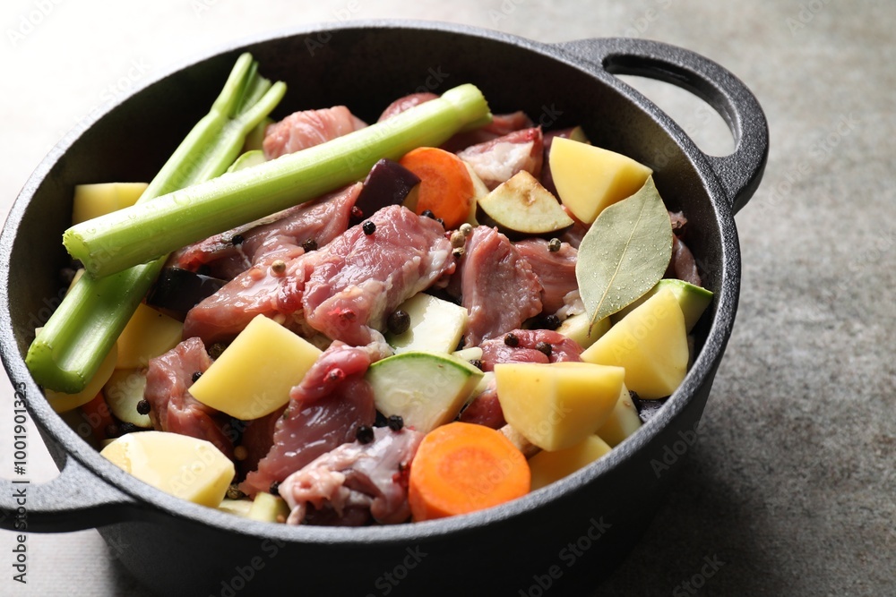Cooking stew. Uncooked meat and vegetables in pot on light grey table, closeup Cooking stew. Uncooked meat and vegetables in pot on light grey table, closeup