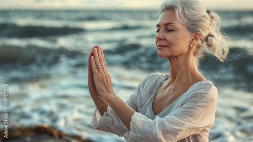 senior woman sitting on the beach practising yoga