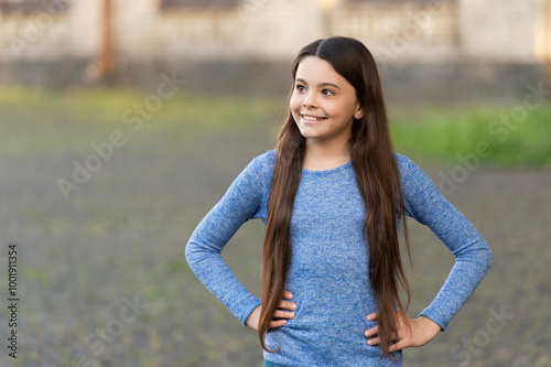 Trendy and stylish teenager girl smiling. Fall fashion style for teen. Complete outfit style. Girl portrait in casual sweater. Long hair. Teen girl with long hair outdoor. Autumn fashion girl. Banner photo
