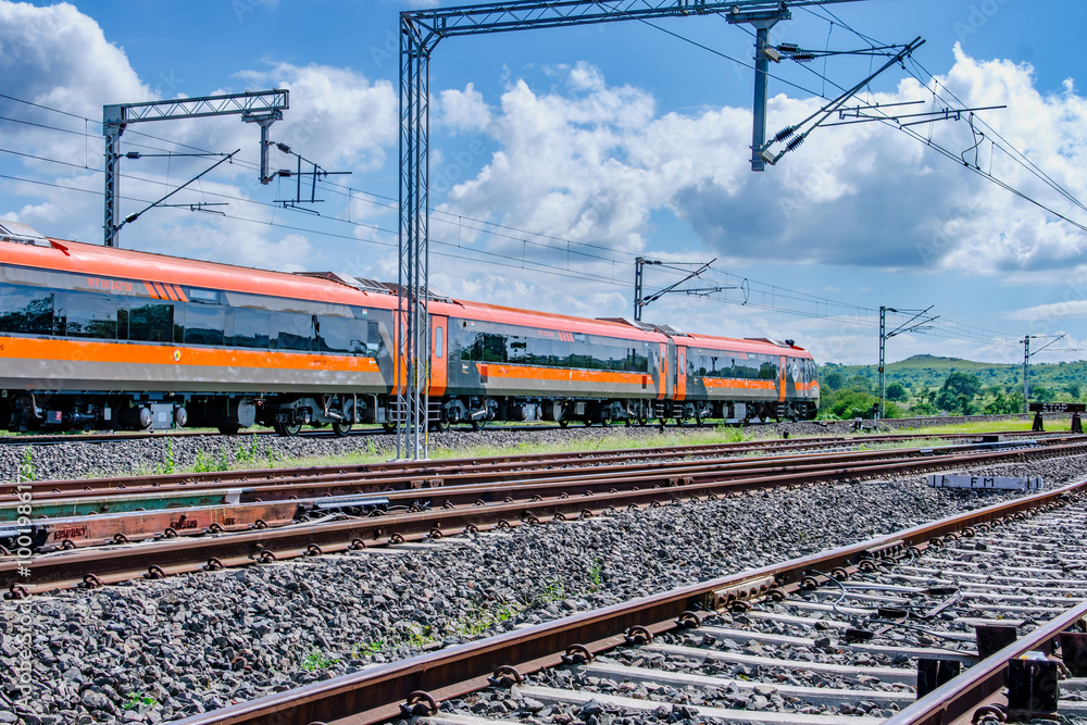 Fototapeta premium Saffron coloured Vande Bharat Express near Pune India. This is a tri-weekly train between Pune and Kolhapur and also a tri-weekly train between Pune and Hubballi.