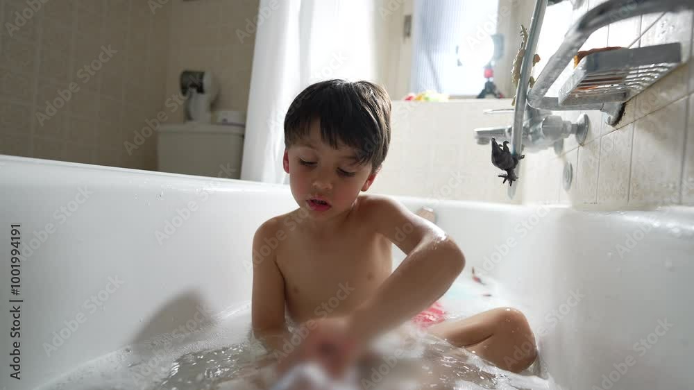 Young boy playing with toy in bathtub, indoor setting, natural light, joyful expression, surrounded by bubbles, casual and fun moment, simple background, childhood and play Young boy playing with toy in bathtub, indoor setting, natural light, joyful expression, surrounded by bubbles, casual and fun moment, simple background, childhood and play