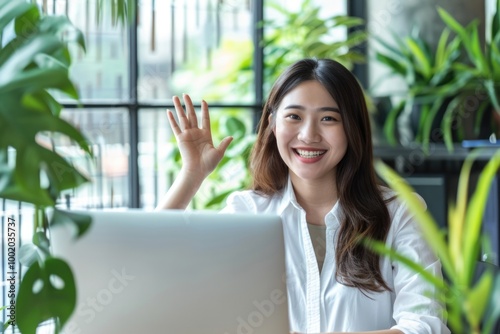 Waving To Computer. Portrait of Asian Businesswoman Working in Modern Office Environment