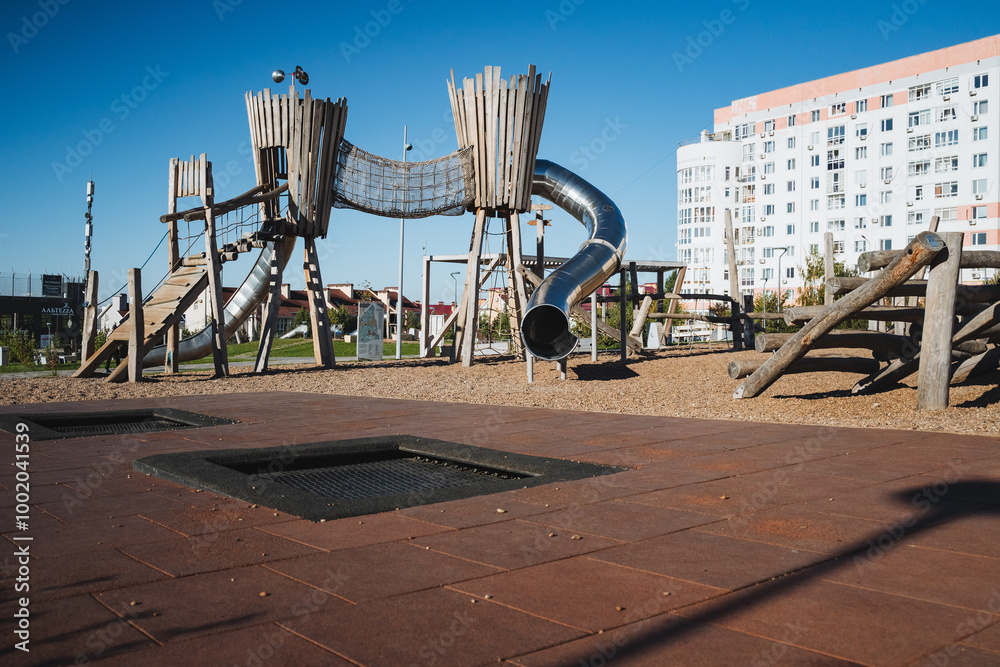 © Aleksey - There is a vibrant playground featuring a large trampoline located right in the center of the area, surrounded by various recreational facilities and play equipment for children © Aleksey - There is a vibrant playground featuring a large trampoline located right in the center of the area, surrounded by various recreational facilities and play equipment for children
