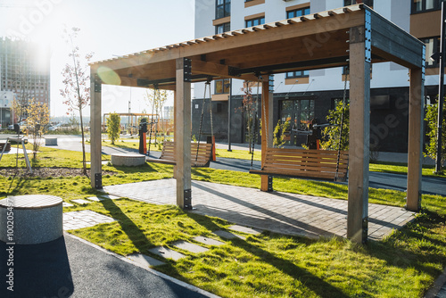 Fototapeta Naklejka Na Ścianę i Meble -  In the center of the park, there exists a beautifully constructed wooden pergola that enhances the outdoor space, providing a charming area for relaxation and leisure activities