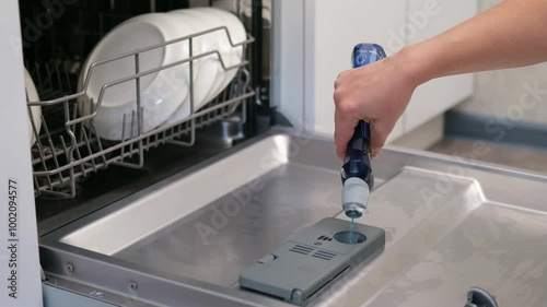 female hand puts dishwasher tablet into open automatic built-in dishwasher machine. Close up

