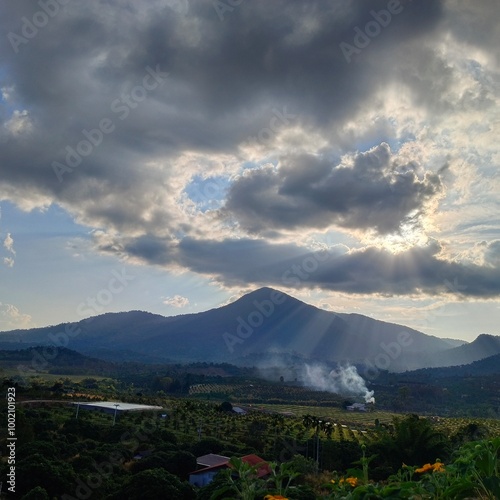 Sunset Over Mountain Landscape with Dramatic Clouds and Sun Rays
