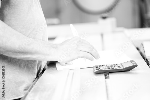 Black and white picture of Carpenter calculating costs in worksh photo